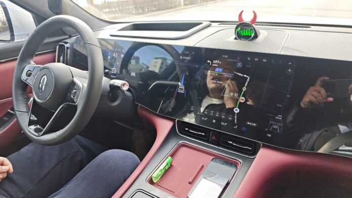 Driver's view inside an AITO M8 in China with Huawei Qiankun ADS 4 driver assistance engaged, showing the steering wheel, driver display and center touchscreen
