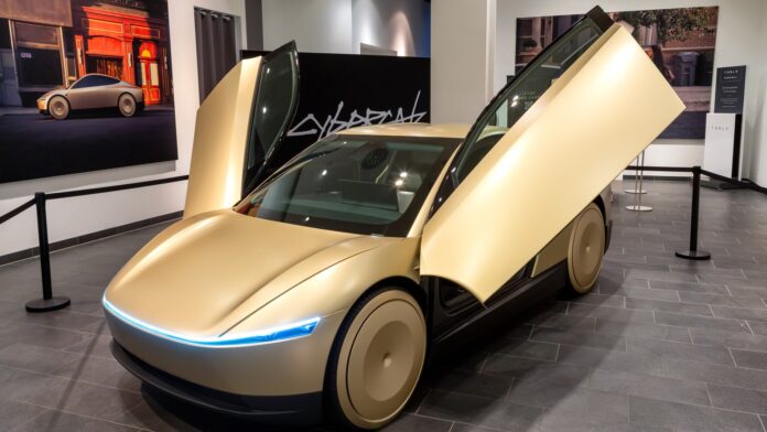 Gold Tesla Cybercab with butterfly doors open on display inside a shopping mall (cropped)