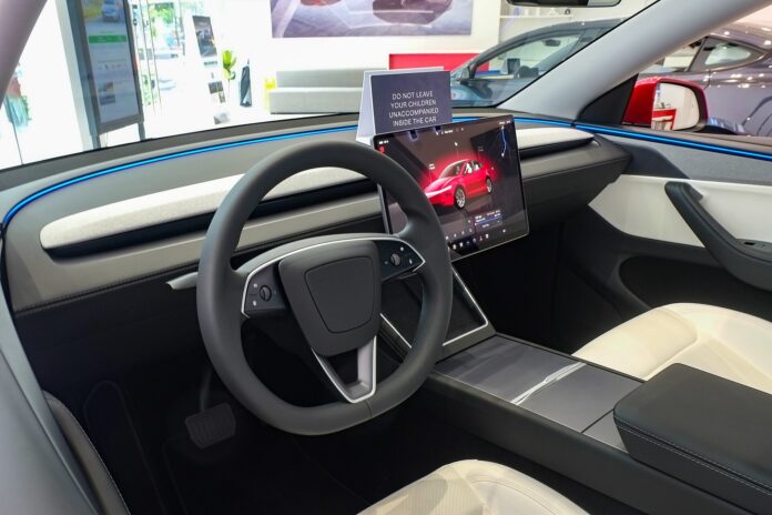 Interior of a 2025 Tesla Model Y showing the steering wheel and central touchscreen