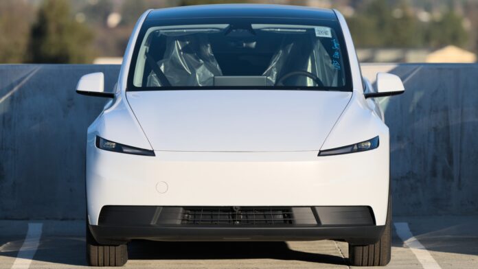 White 2025 Tesla Model Y seen head-on in a rooftop parking lot (cropped)